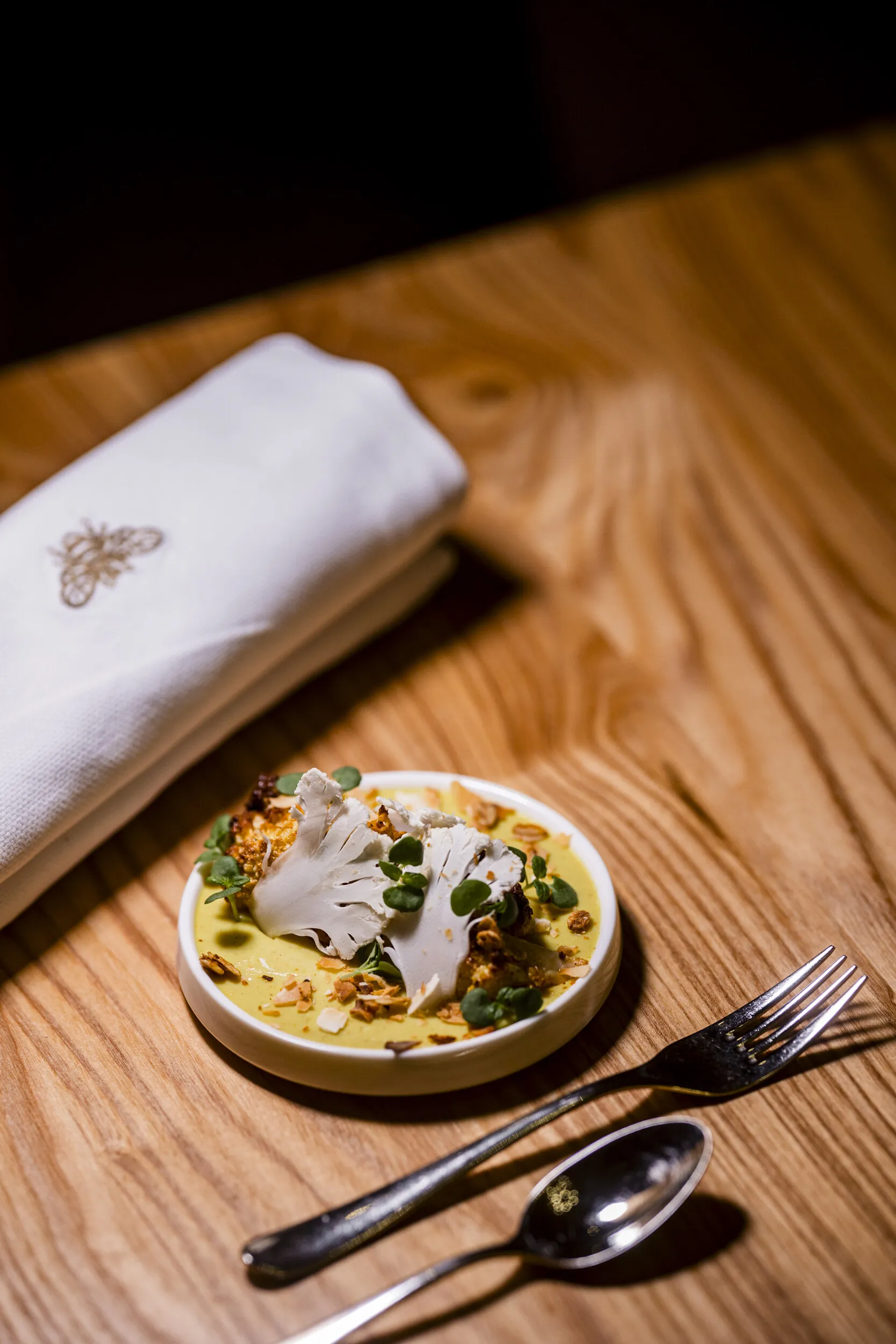 Serviette mit Bienen-Stickerei und angerichteter Teller